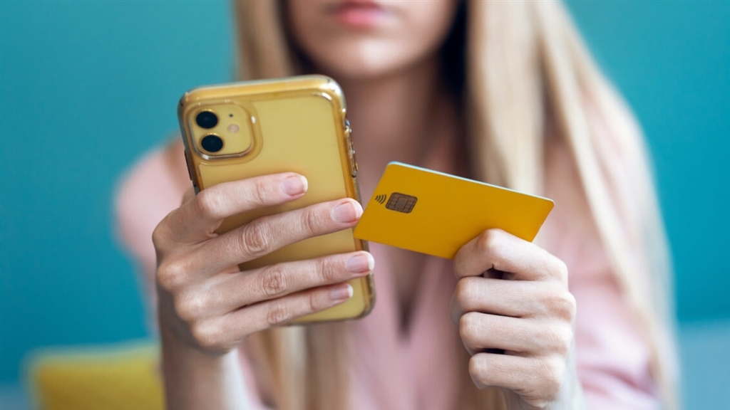 Milennial looking at phone and credit card
