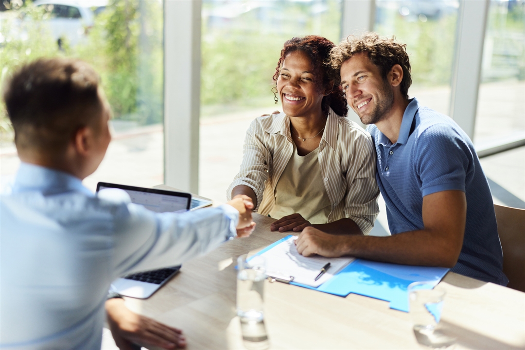 Couple talking with an advisor shaking hands