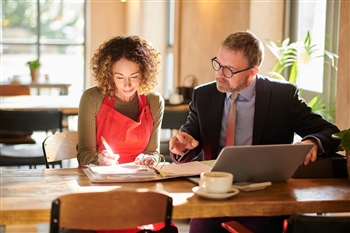 Female business owner signing lending papers with banker