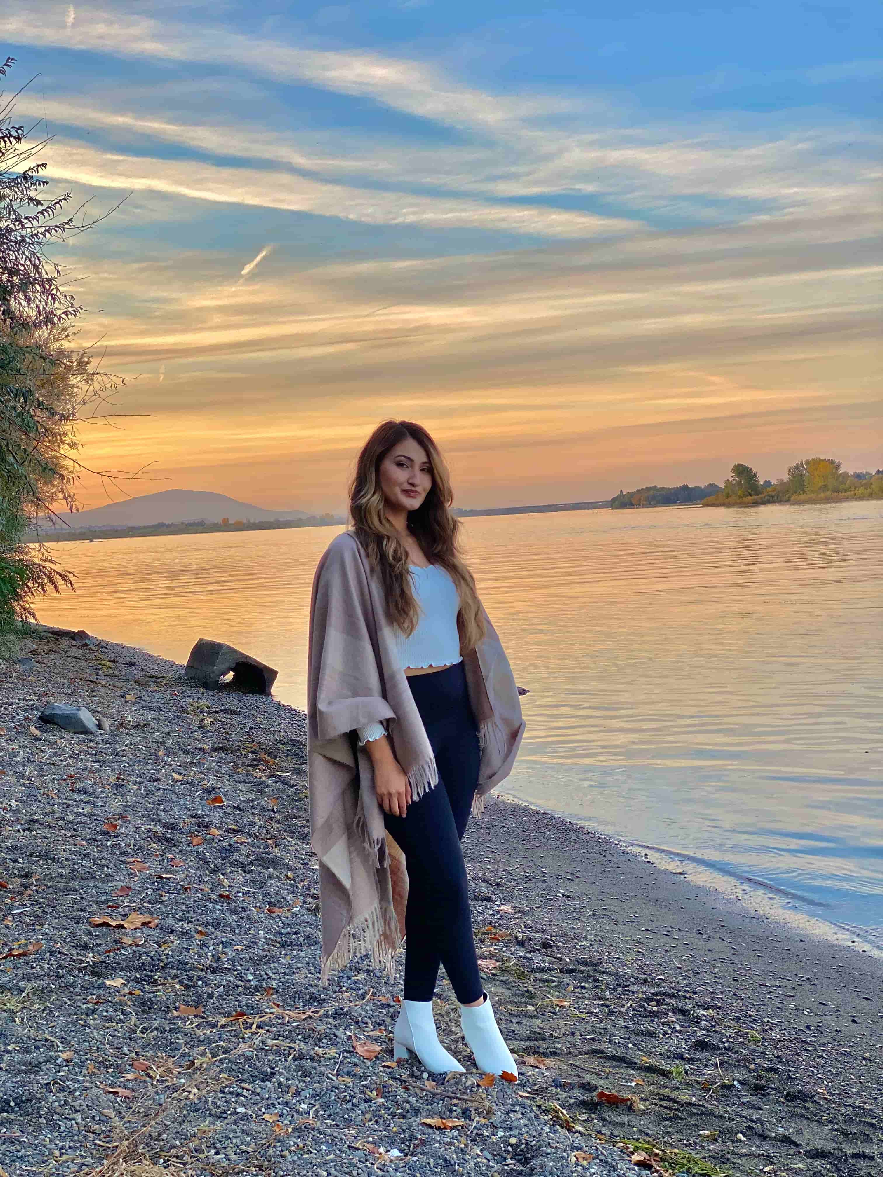 Marlena Ramirez by a body of water with a sunset behind her