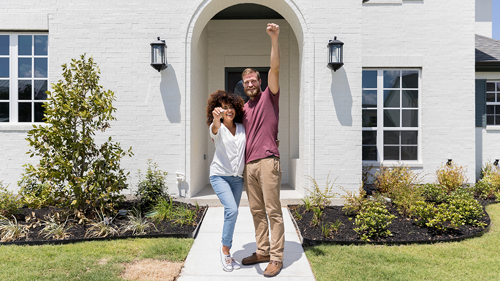 Couple holding up keys in front of house