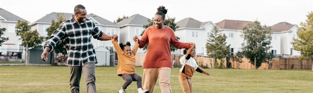 African American family of four holding hands and walking together