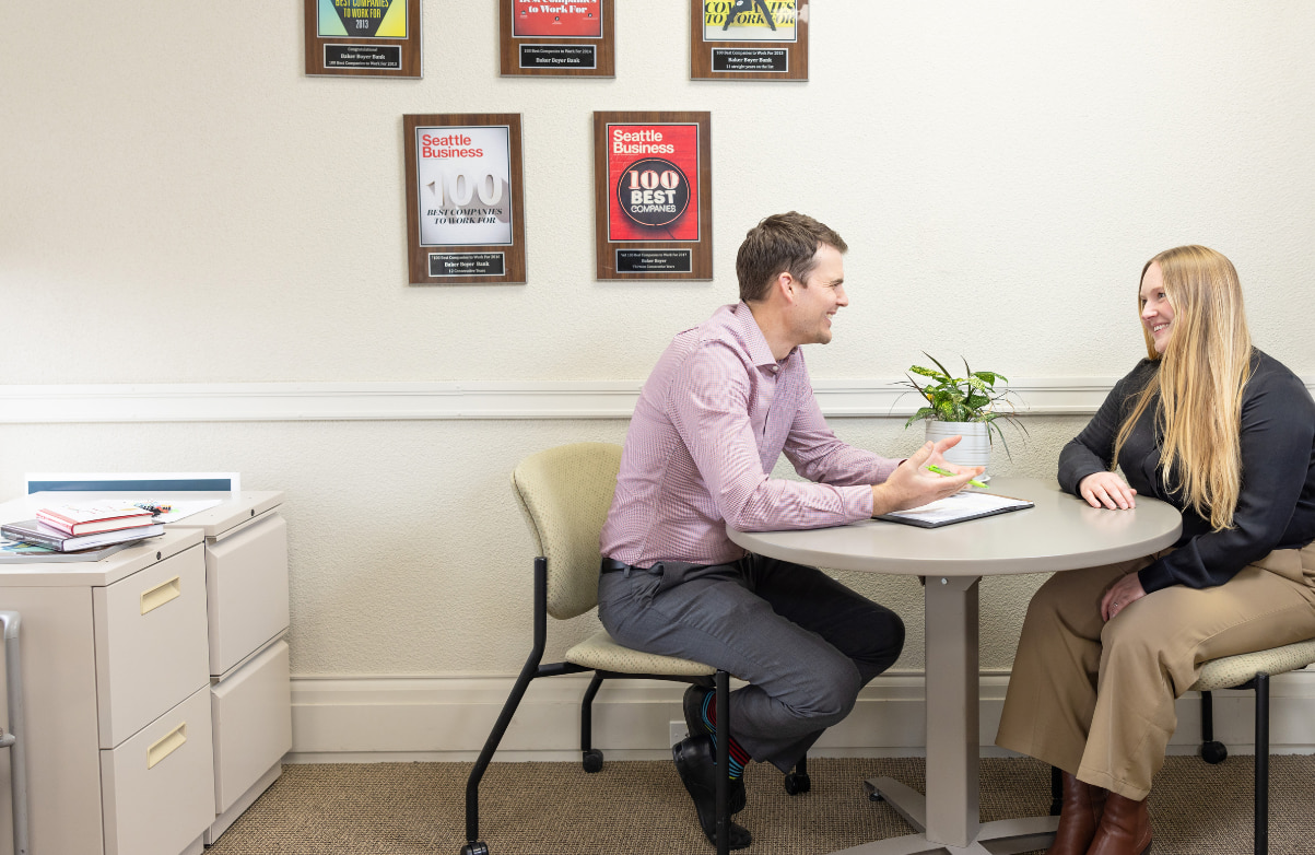 Bank employees meeting at table in front of award plaques