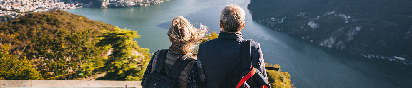 boomer couple on mountain looking out into a valley