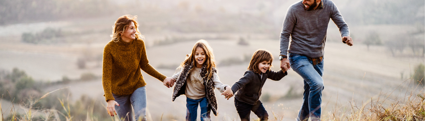 Family of four holding hands walking, wealth management