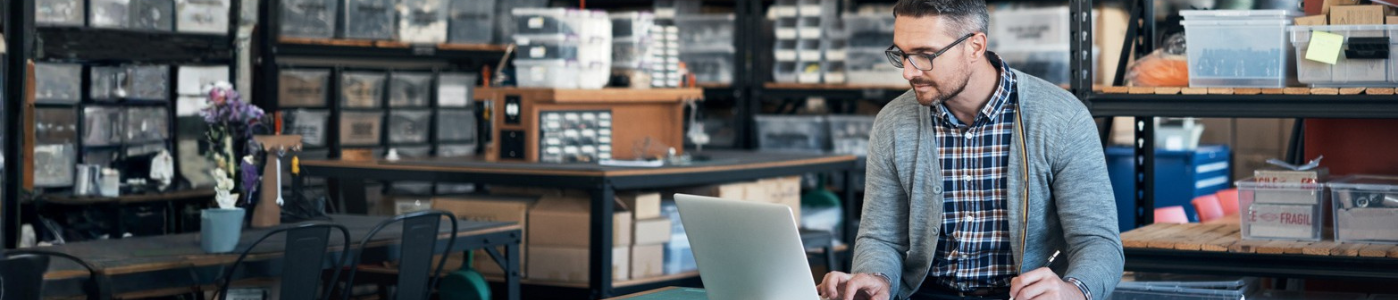 Man typing on laptop in warehouse